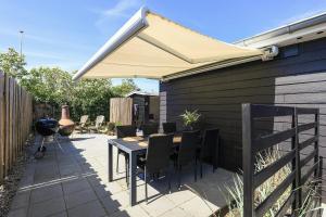 an umbrella on a patio with a table and chairs at Holiday Home With A Direct Path To The Sea in Korsør