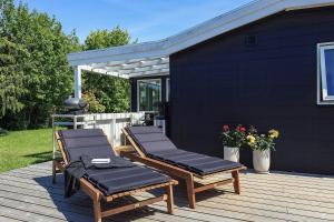 two lounge chairs on a deck with a black building at Holiday Home With A Direct Path To The Sea in Korsør