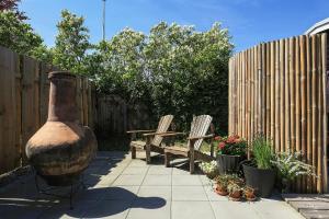 a garden with two benches and a large vase and a fence at Holiday Home With A Direct Path To The Sea in Korsør +29 photos