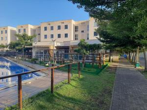 a building with a walkway next to a body of water at Apto 2Q com Area de Lazer e Piscina in São Gonçalo do Amarante