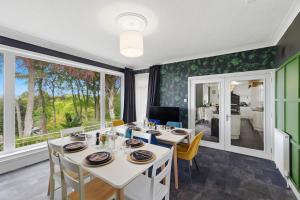 a dining room with a table and chairs and windows at Five Marches - Poolside Stays with Stunning Views in Angus