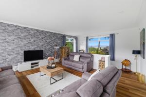 a living room with a couch and a tv at Five Marches - Poolside Stays with Stunning Views in Angus