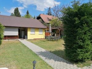 a yellow house with a table and an umbrella at Veronica nyaralóház in Zamárdi