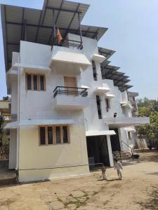a white building with people standing in front of it at Shashtri nagar AC homestay in Kolhapur