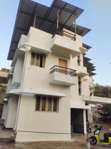 a white building with a balcony on top of it at Shashtri nagar AC homestay in Kolhapur