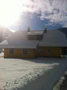 a yellow house with snow on the roof at Ferienhaus Strasswirt in Jenig