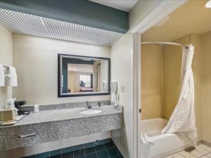 a bathroom with a sink and a tub and a mirror at Hotel Blue Baytown, Texas in Baytown