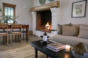 a living room with a couch and a table with a bottle of wine at Vineyard Cottage at Bosman Wines in Wellington +19 photos