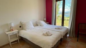 a bedroom with a bed with white sheets and a window at Villa Salagou - Vue sur le lac - Liausson 34800 - 6-8 pers - 100m2 in Liausson +25 photos