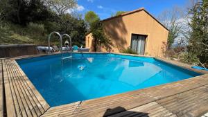 a swimming pool with a wooden deck next to a house at Villa Salagou - Vue sur le lac - Liausson 34800 - 6-8 pers - 100m2 in Liausson