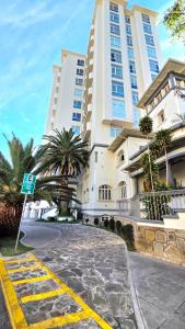 a large white building with palm trees in front of it at TORREMIA apartamentos de lujo in Cochabamba