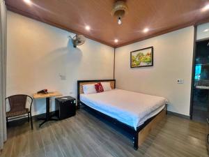 a bedroom with a bed and a table and a chair at Hideaway Village Homestay in Xuân Sơn