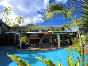 a resort with a swimming pool in front of a building at Crystal Garden Resort & Restaurant in Cairns