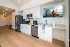 a kitchen with white cabinets and a tv on the wall at Harbor View 101 in Morro Bay