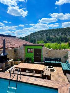 a swimming pool with a wooden deck and a house at El nido del Mirlo in Casarejos