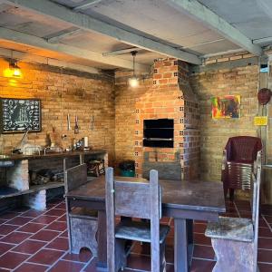 a kitchen with a wooden table and a brick wall at Chácara Luz do Vale in Votuverava