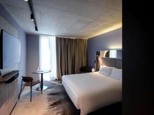 a hotel room with a white bed and a table at Mercure Hotel Delémont in Delémont +49 photos