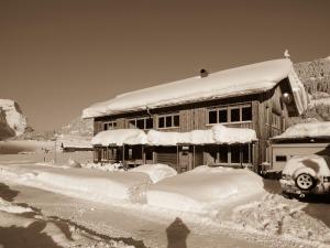 ein schneebedecktes Haus mit viel Schnee drauf in der Unterkunft Appartements Madlener in Schoppernau