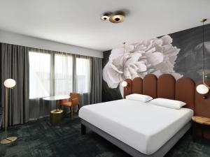 a bedroom with a bed with a painting on the wall at Mercure Debrecen in Debrecen