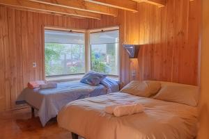 zwei Betten in einem Zimmer mit Fenster in der Unterkunft Impresionante casa + Starlink | Bosque y estufa in Pucón