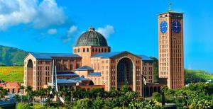 a large building with a clock tower and a building with a church at Ecos Jatobá - Refúgio à 12 km do Santuário de Aparecida in Guaratinguetá