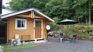 a small house with a table and an umbrella at こや・かやき in Yufu