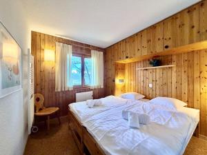 a bedroom with a large white bed in a wooden wall at Eanta SUNNY & MOUNTAIN chalet 10 pers by Alpvision Résidences in Veysonnaz