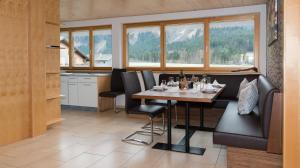 ein Esszimmer mit einem Tisch, Stühlen und Fenstern in der Unterkunft Appartements Madlener in Schoppernau