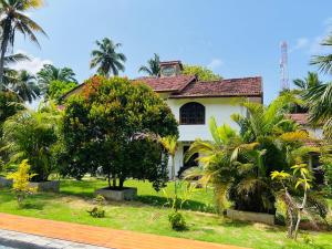 a white house with a clock tower on top of it at Sunny's Garden Hotel in Ambalangoda