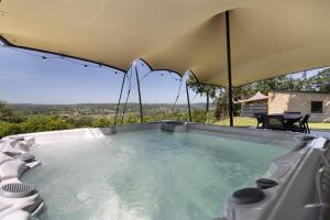 a hot tub with an umbrella on top of it at Le Pech Eternel-Lodge Spa Tilleuls in Sarlat-la-Canéda