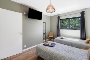 a bedroom with two beds and a flat screen tv at Le Pech Eternel - La Truffière in Sarlat-la-Canéda