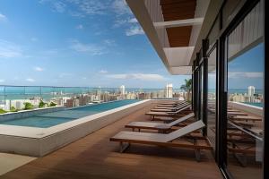 a pool on the roof of a building with lounge chairs at Beach Class Meireles by HostFacil in Fortaleza