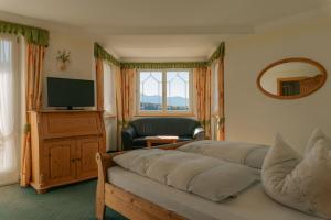 ein Wohnzimmer mit Sofa und Fernseher in der Unterkunft Hotel Roduna in Rodeneck