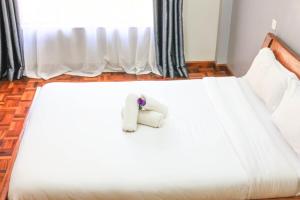a white bed with a stuffed animal on it at Legacy Homes in Nairobi +5 photos