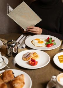 a person sitting at a table with plates of breakfast food at Rosa Grand Milano - Starhotels Collezione in Milan +214 photos