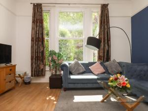 a living room with a blue couch and a window at Apartment 2 in Torquay