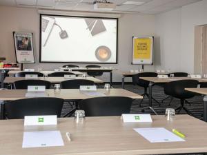 a classroom with tables and chairs and a large screen at ibis Styles Porto Vecchio in Porto-Vecchio +71 photos
