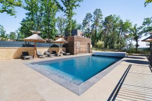 a swimming pool with two chairs and umbrellas at Le Pech Eternel - La Sablière in Sarlat-la-Canéda