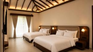 a bedroom with two beds and a window at La Damai in Aldūr