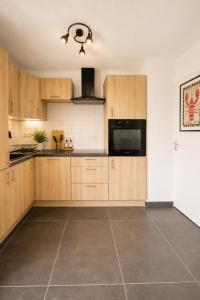 a kitchen with wooden cabinets and a tile floor at Charmant T2 Bordeaux Proche tram & centre-ville in Bruges