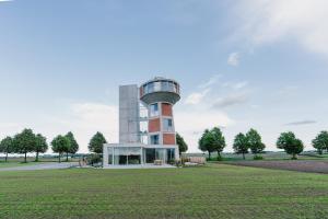 a building with a tower in the middle of a field at De Droomtoren - uniek overnachten in een watertoren nabij Maastricht in Riemst