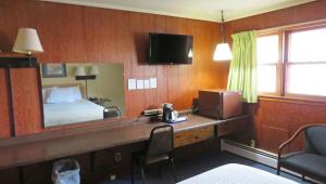 a bedroom with a bed and a desk with a television at Indianhead Ironwood Hotel in Ironwood
