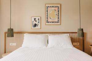 a bedroom with a white bed with two pendant lights at Hotel Apollon Corfu in Paleokastritsa