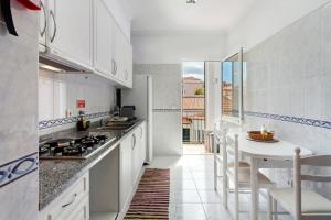 a kitchen with white cabinets and a table and a counter at Paradise Dream in Caniço