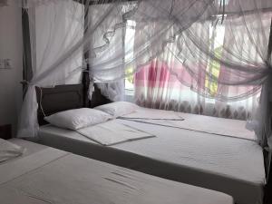 due letti in una stanza con finestra di Hotel Blue Sky a Hikkaduwa