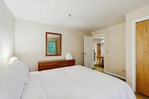 a bedroom with a large white bed and a mirror at Seasons 207 in Warren