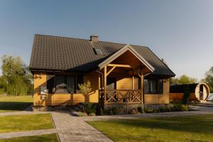 a wooden house with a black roof at Mościce Dolne 69 in Nowosiółki