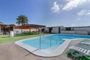 a large swimming pool with chairs and a table at Villa Jomeca in Salobre