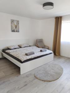 a white bedroom with a bed and a rug at Dömper Döme Apartman 1E in Balatonlelle