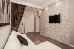 a living room with a couch and a tv on a stone wall at Magia in Trastevere in Rome